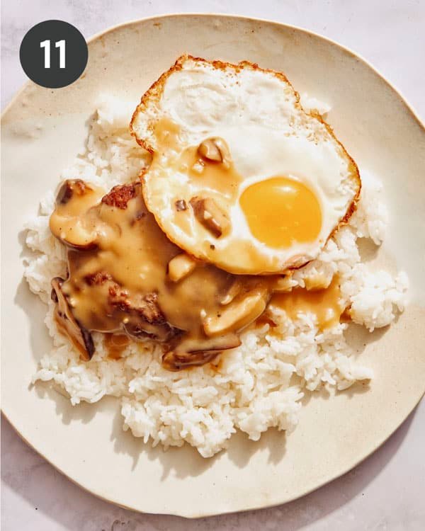 Building a plate of Loco Moco with a fried egg on top.