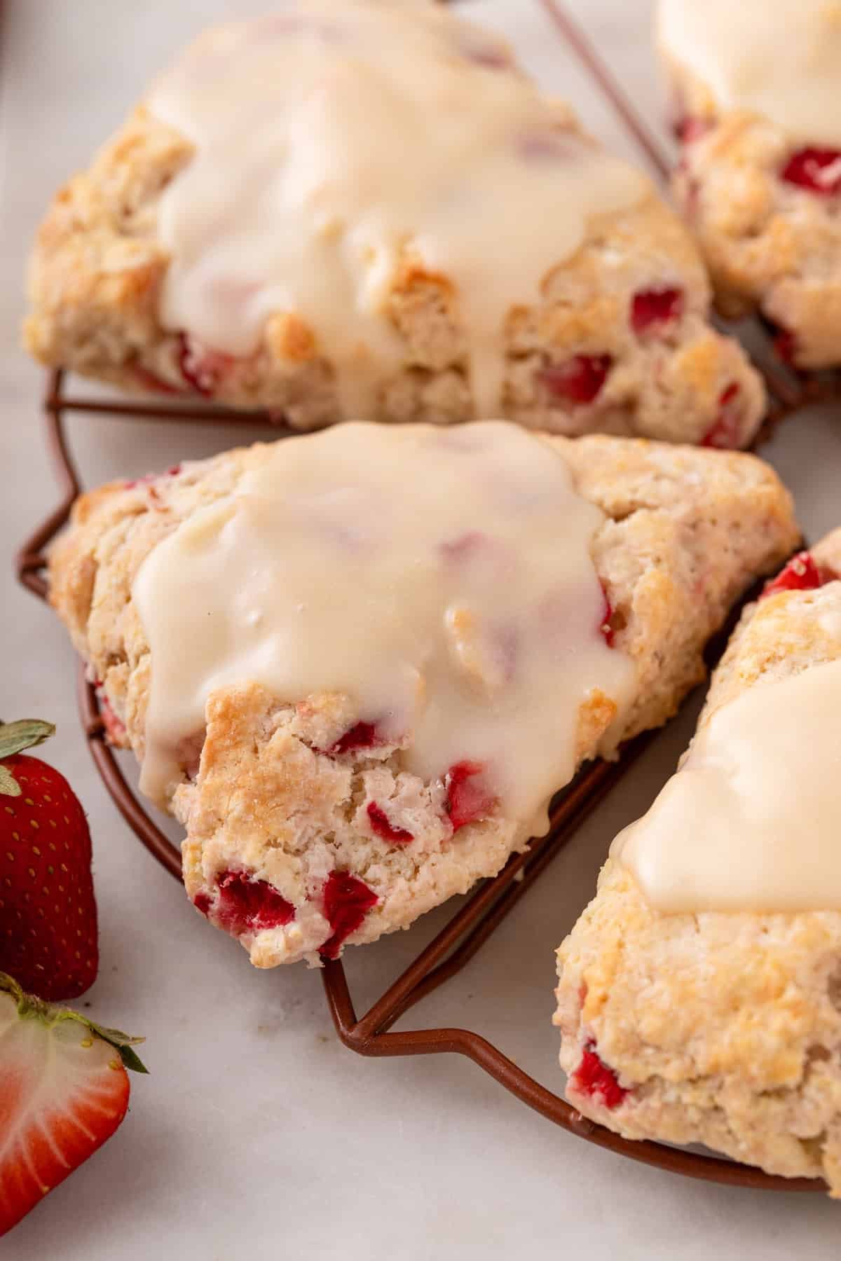 Close up of glazed strawberry scones on a wire rack.
