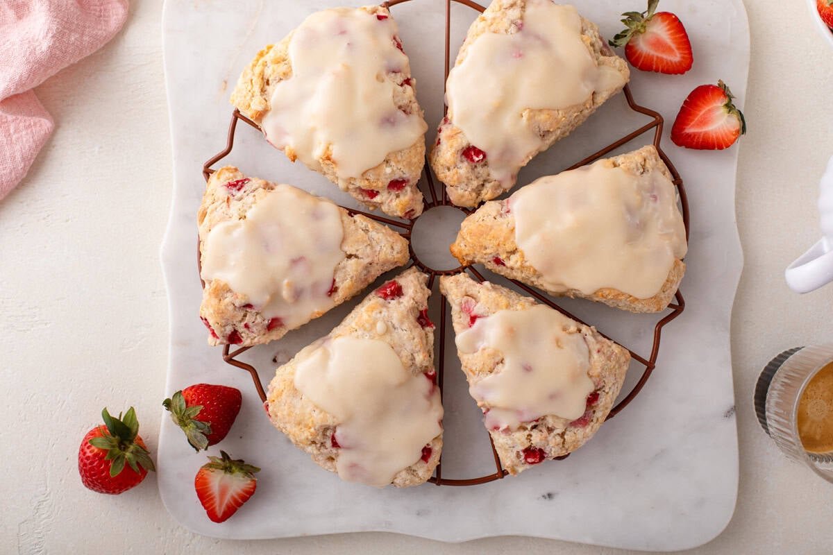 Overhead view of glazed vanilla scones arranged in a circle on a wire rack.