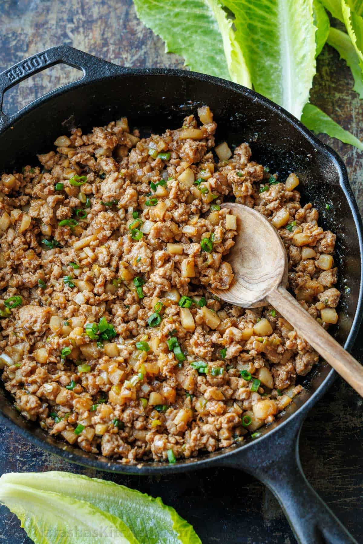 Chicken lettuce wrap filling in a cast iron pan with water chestnuts and green onions