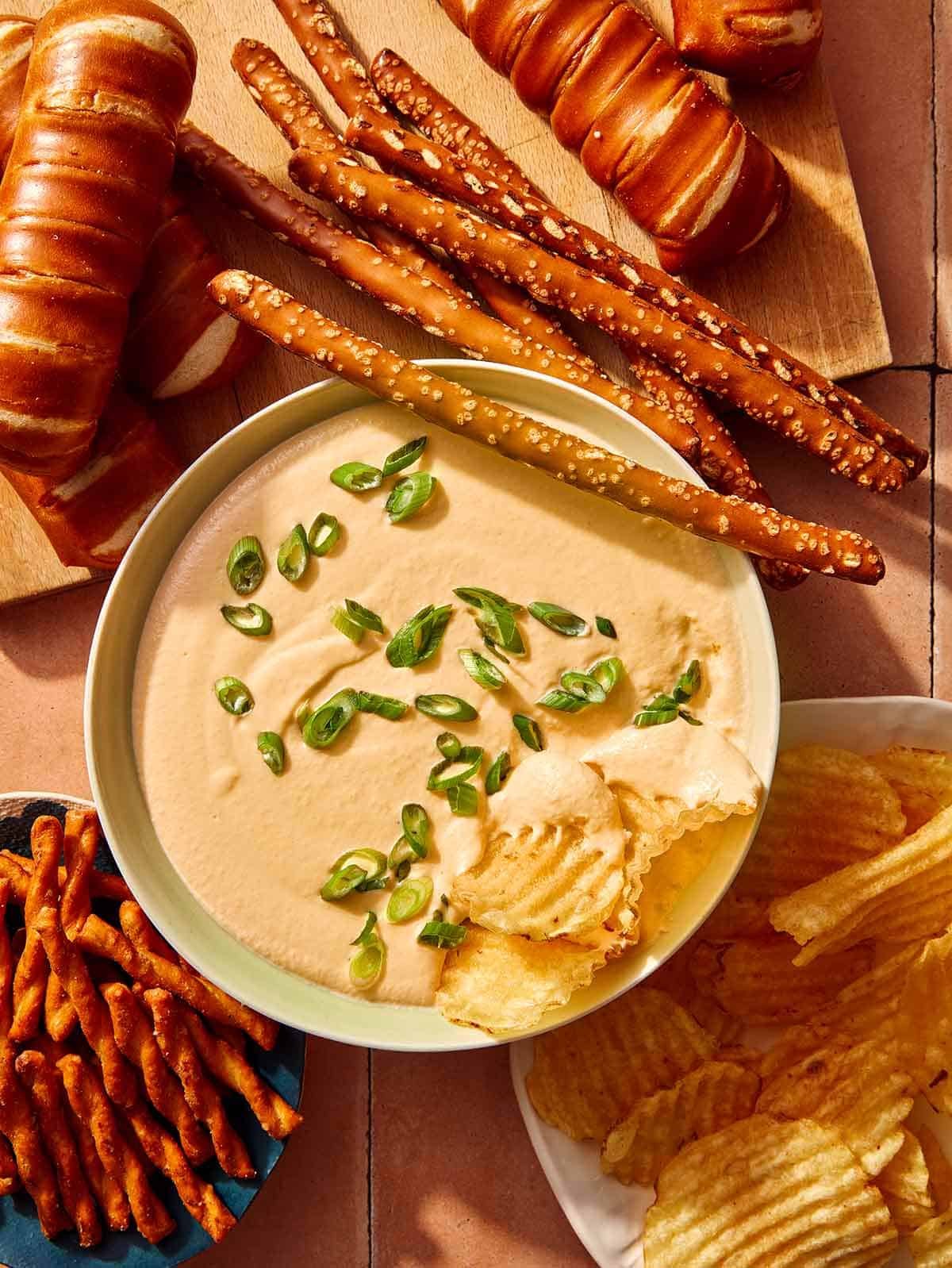 Crock pot beer cheese dip in a bowl with bread and chips all around it. 