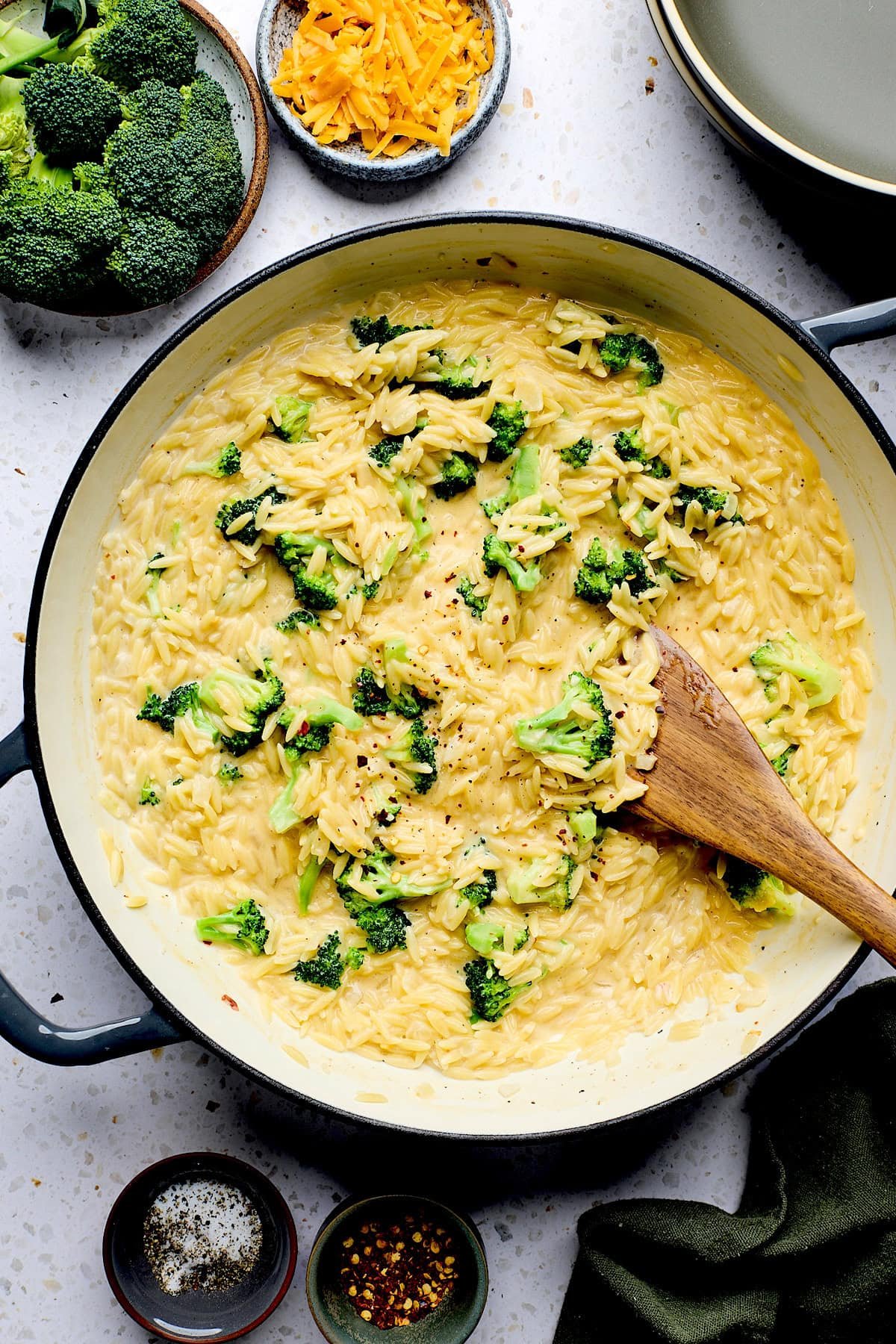 broccoli cheddar orzo in pan with wooden spoon.