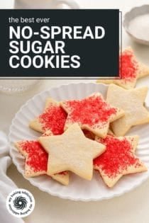 Star-shaped sugar cookies decorated with red and white sparkling sugar arranged on a white plate with a glass of milk in the background. Text overlay includes recipe name.