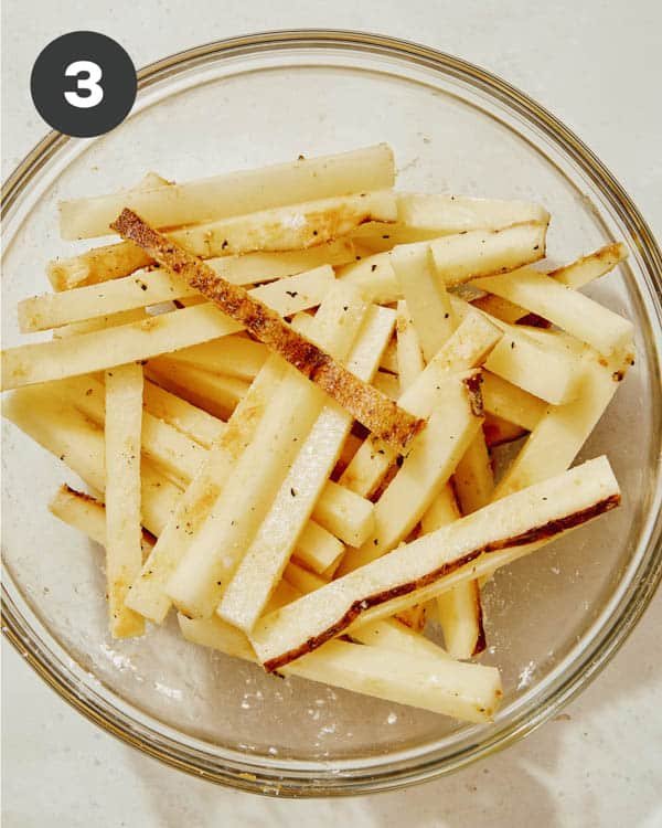 French fries seasoned in a bowl with salt and pepper.