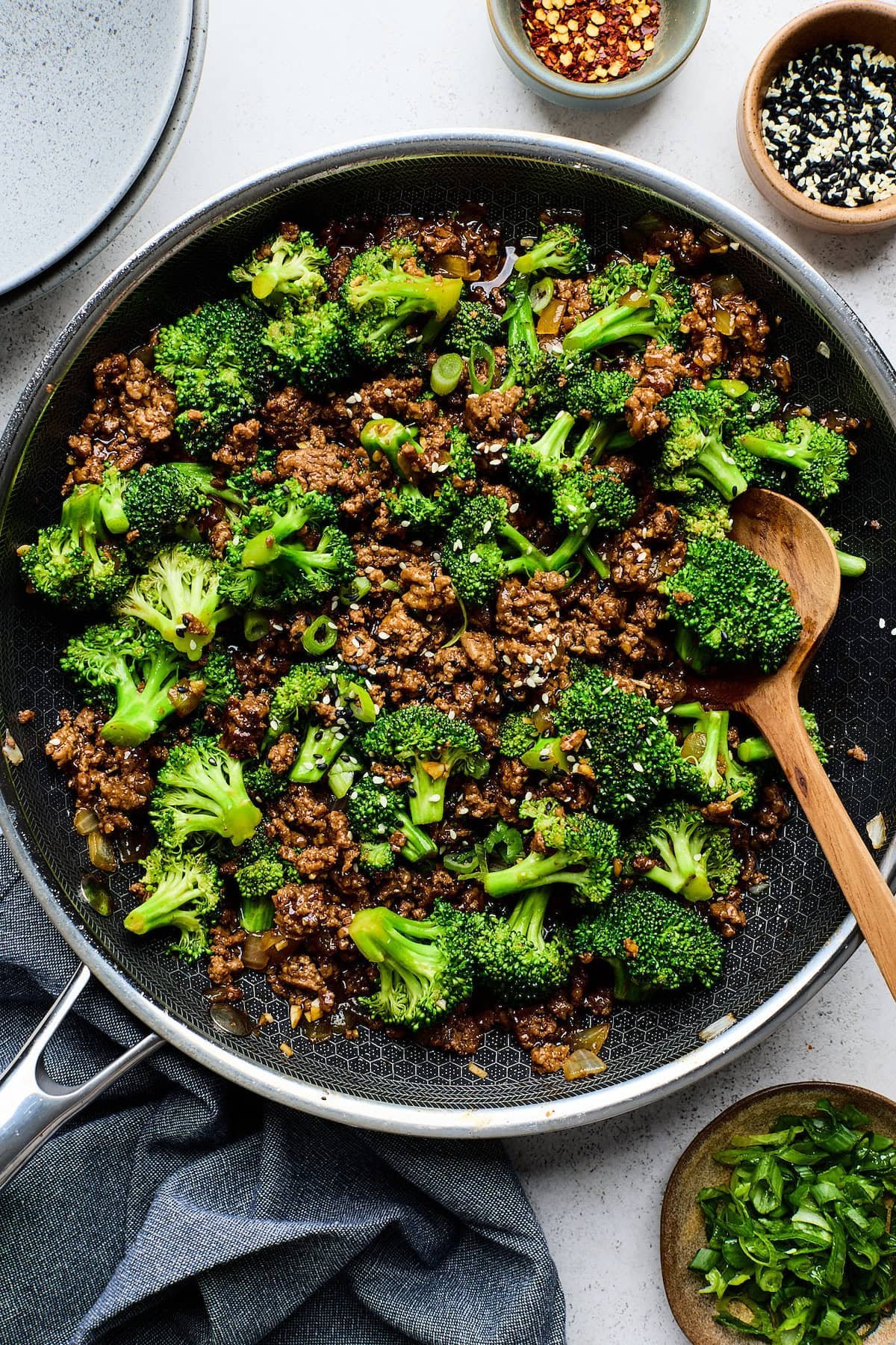ground beef and broccoli in pan with wooden spoon. 