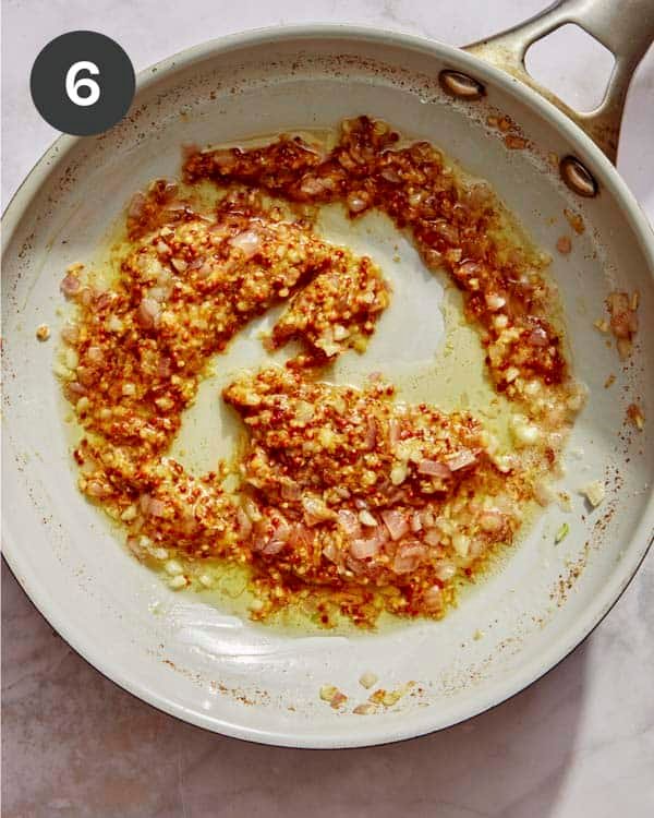 Mustard with garlic and shallots cooking in a skillet.