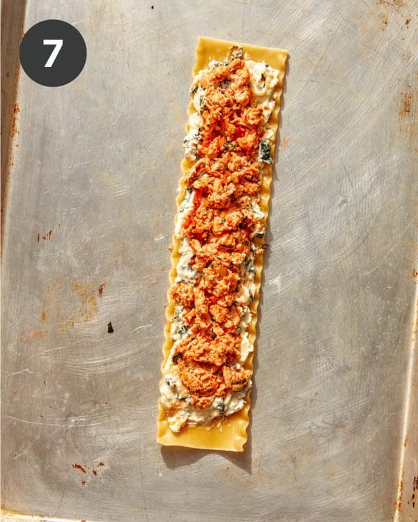 A sheet of lasagna with ricotta and a ground turkey mixture spread on it.