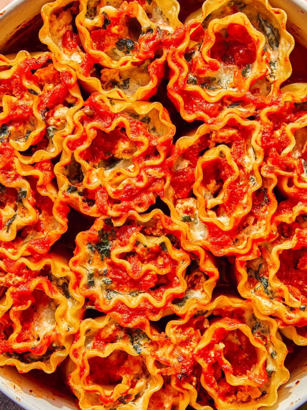Close up overhead shot of lasagna roll ups in a baking dish.