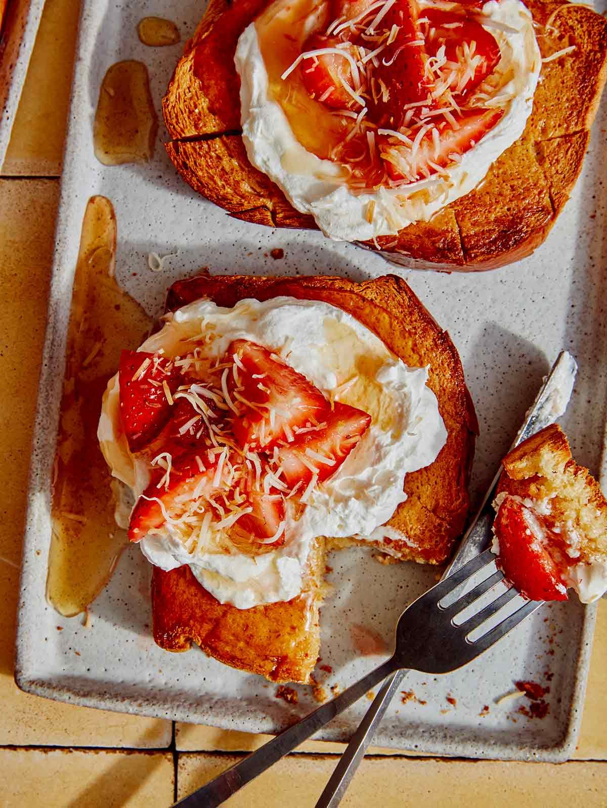 Honey toast being cut into with a fork and knife on a plate. 