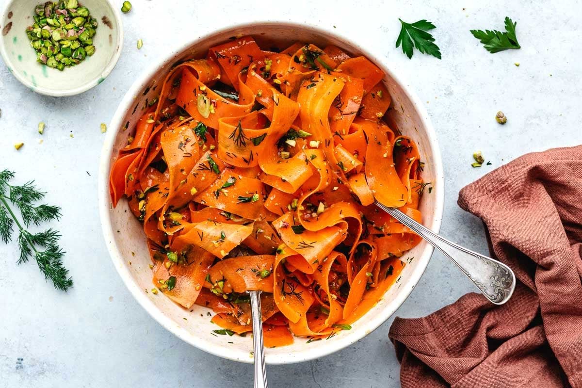 carrot ribbon salad in bowl with serving spoons. 