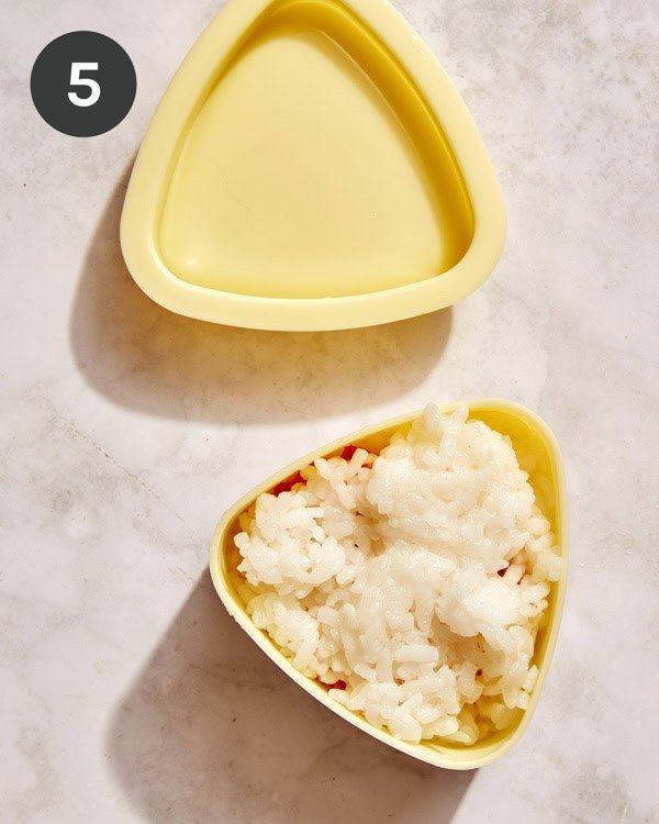 Tuna onigiri in a mold about to be pressed.