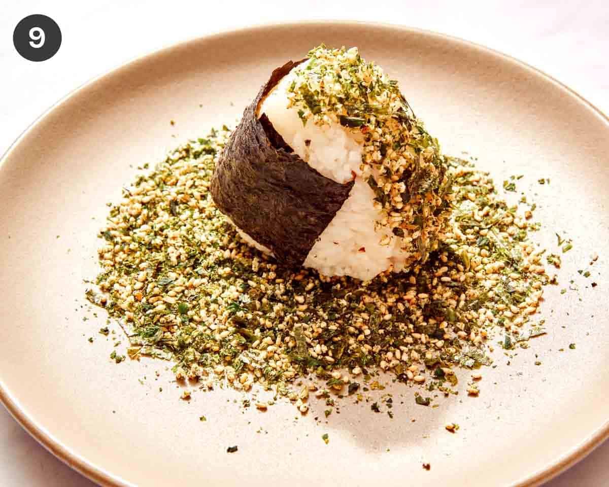 Spicy tuna onigiri being dredged in furikake.