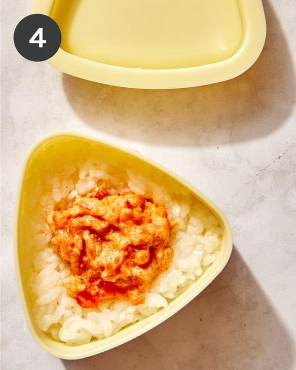 Spicy tuna onigiri being put into an onigiri mold.