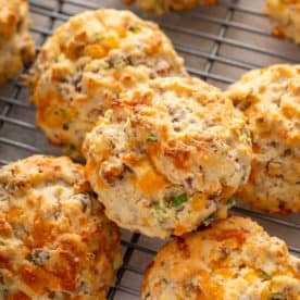 Cheesy sausage biscuits stacked on a wire rack.