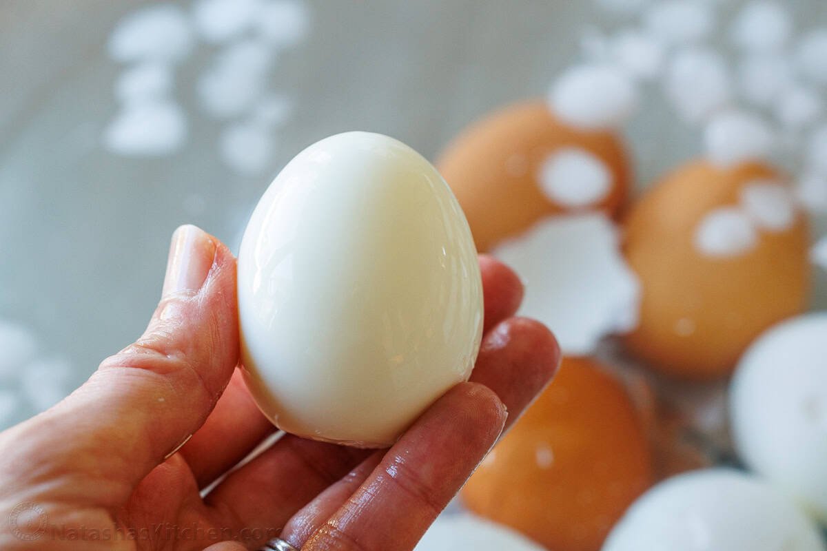 hard boiled egg with shell removed and brown eggs in the background