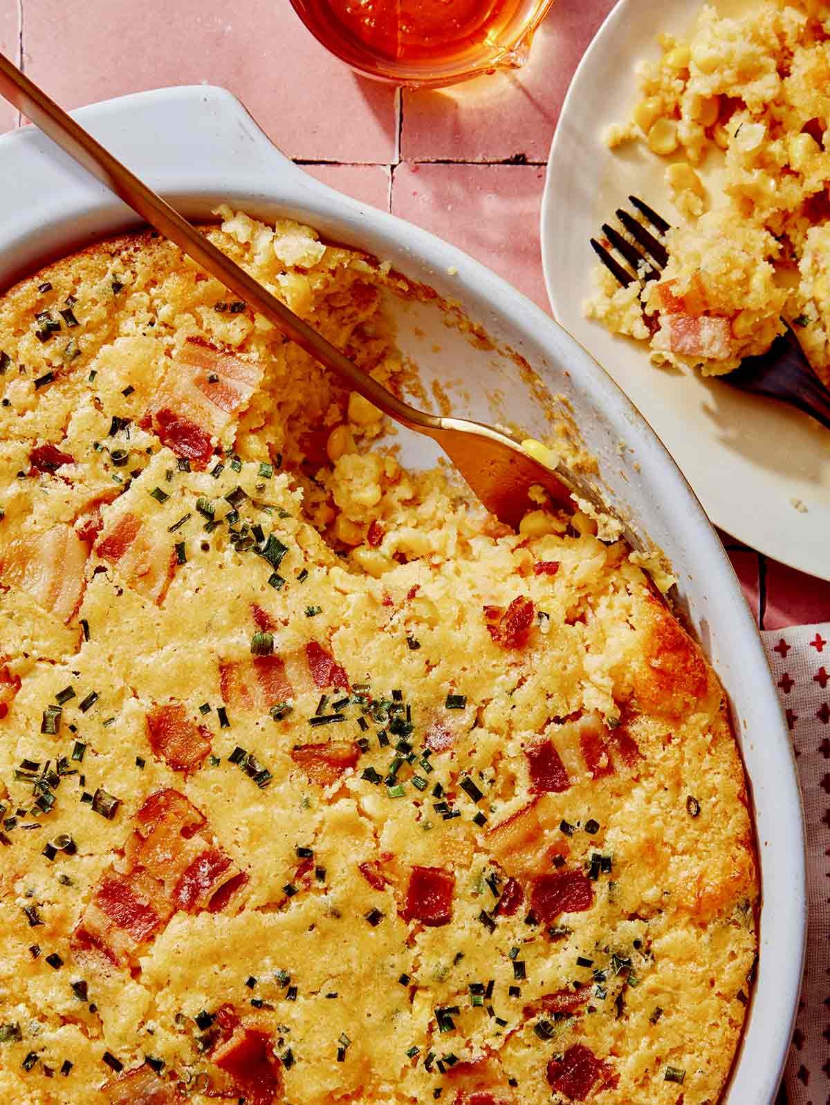 Corn casserole in a baking dish with a plate next to it.