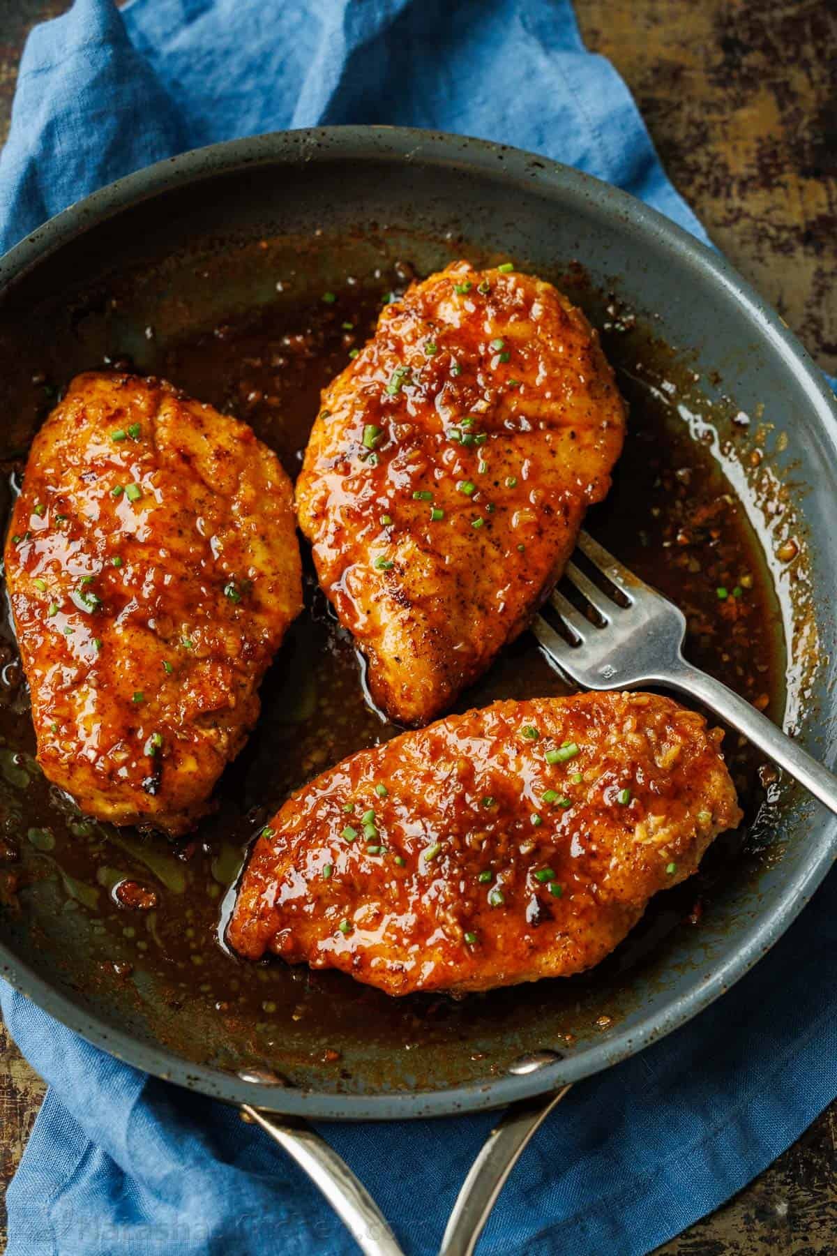 Honey glazed chicken in a saute pan garnished with green onions.