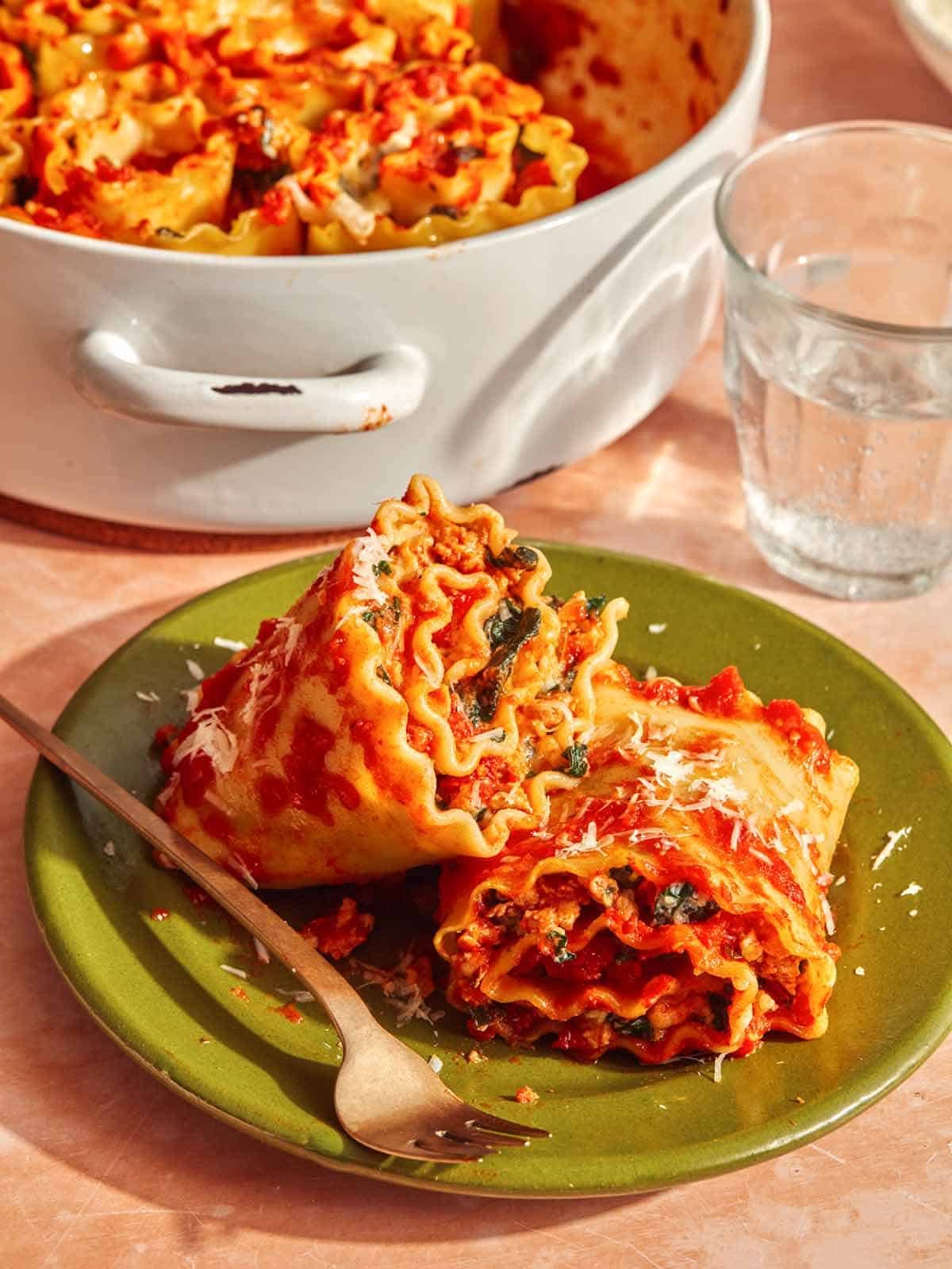 A close up shot of two lasagna roll ups on a plate about to be eaten.