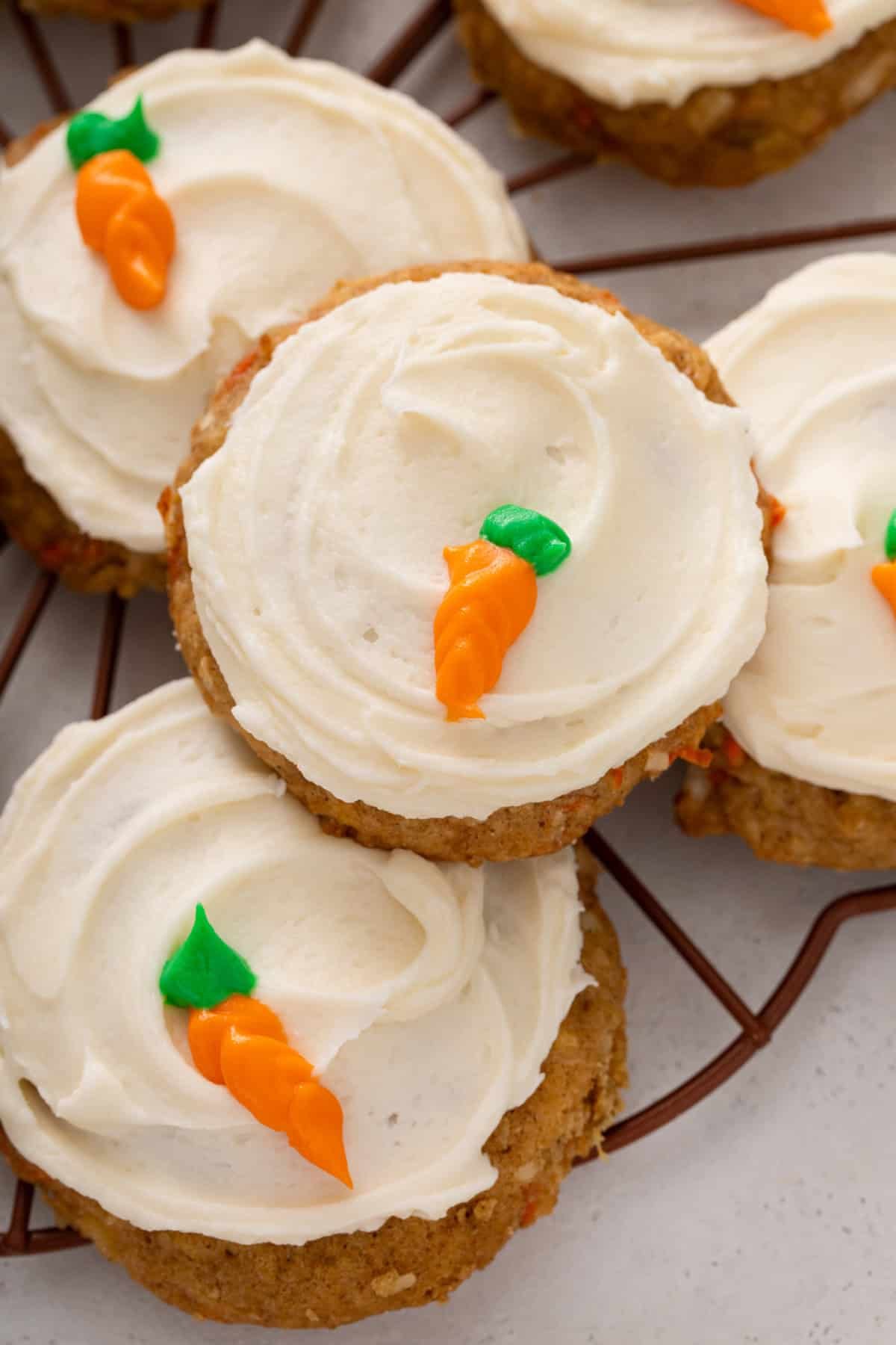 Close up view of frosted carrot cake cookies decorated with icing carrots.