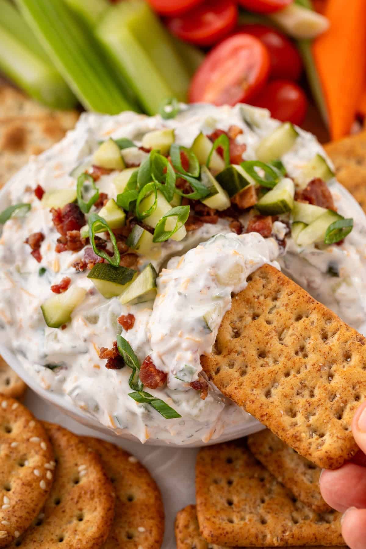 Cracker being dipped into a bowl filled with Grillo's pickle dip.