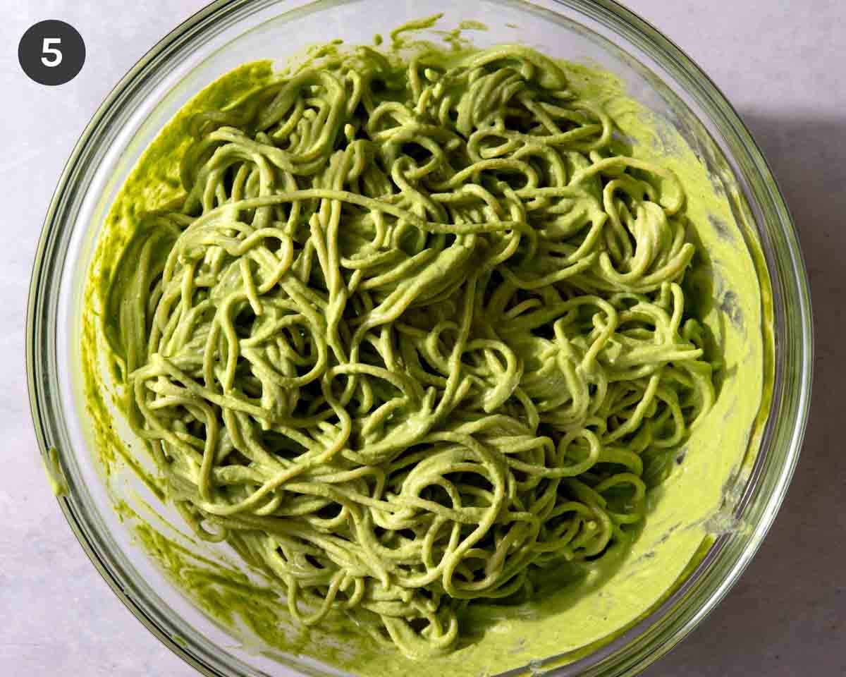 Tallarines verde in a glass bowl all mixed together.