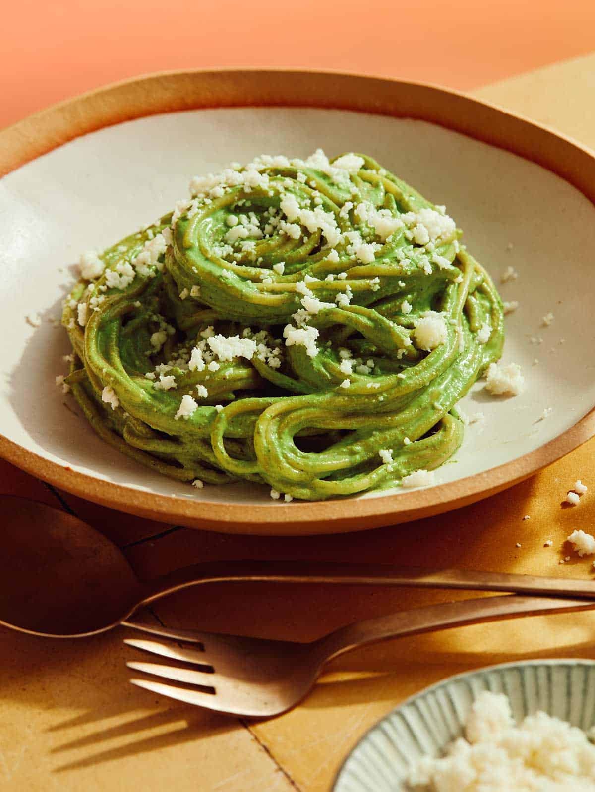 Tallarines Verde recipe in a bowl close up with some queso fresco sprinkled on top.