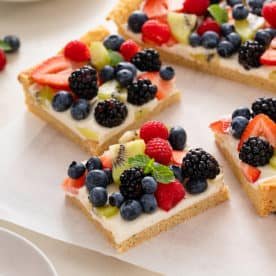 Slices of fruit pizza on a piece of parchment paper.