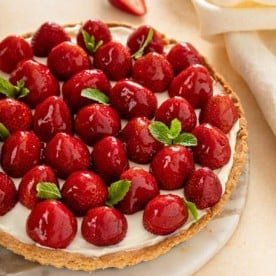 Strawberry tart, garnish with sprigs of mint, set on a marble serving platter.