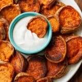 Smashed sweet potatoes with lemon garlic dipping sauce served on a white plate