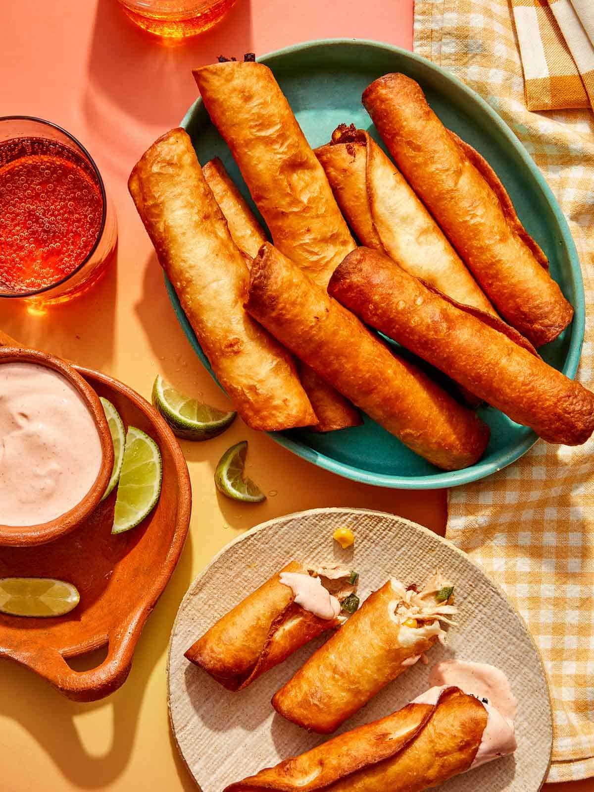 Freshly made Flautas recipe with one torn in half on a plate with some dipping sauce.