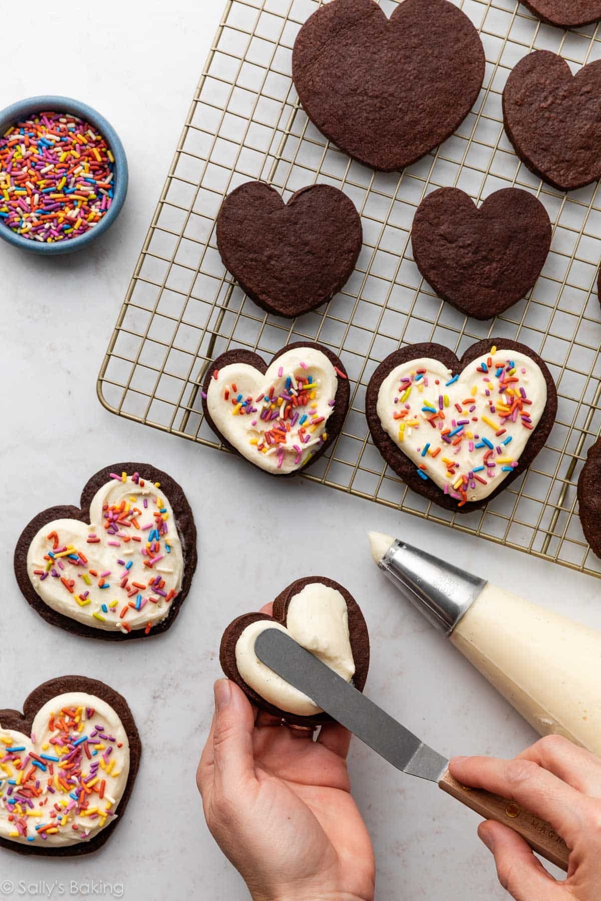 spreading buttercream on chocolate sugar cookies.