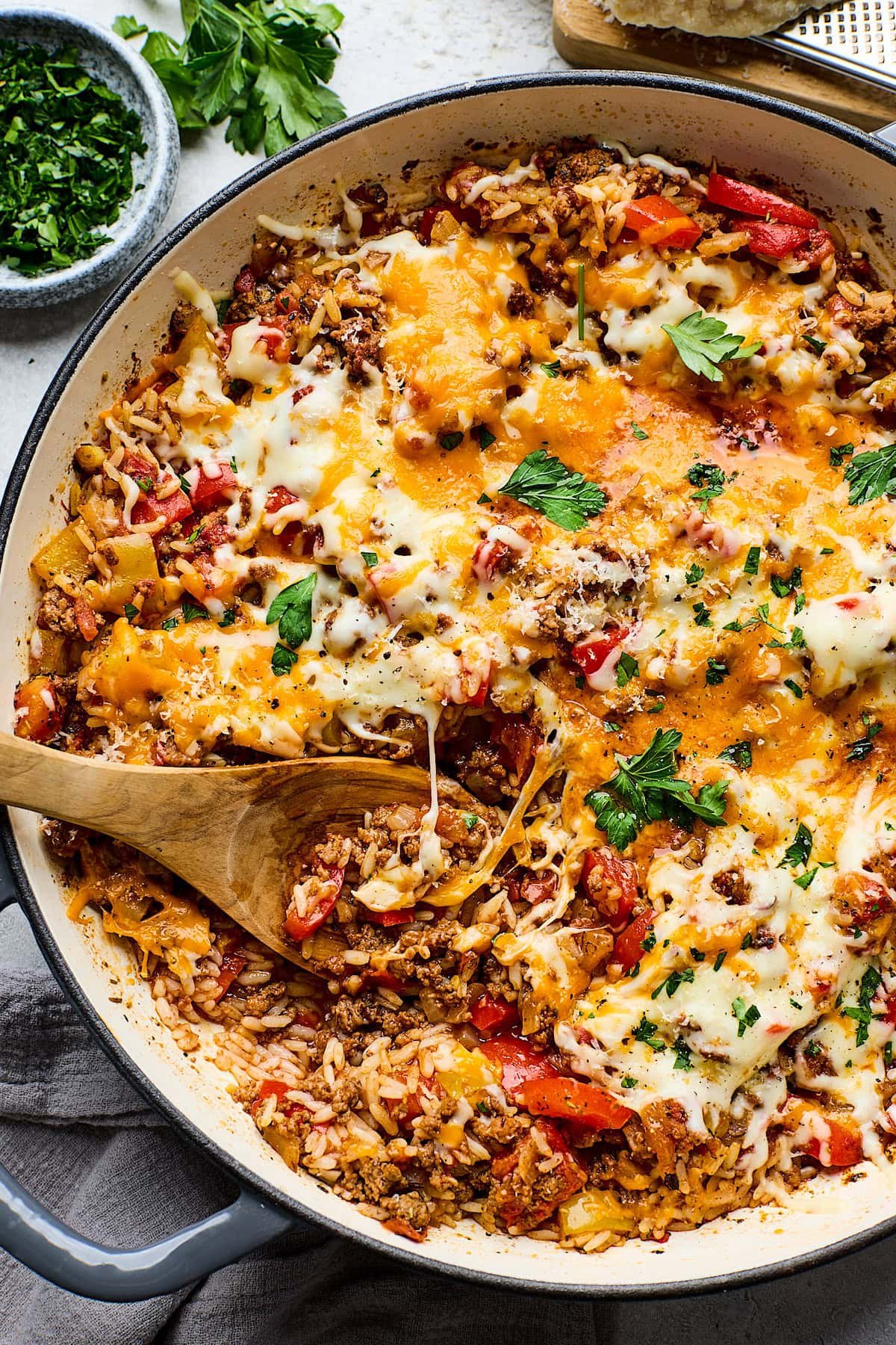 cheesy stuffed pepper skillet being served with a wooden spoon. 