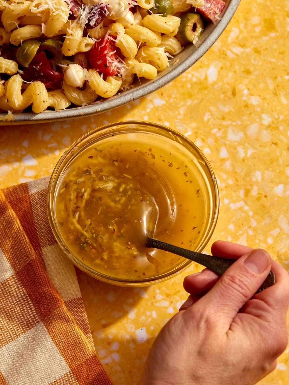 Italian vinaigrette dressing in a jar being mixed with a spoon.