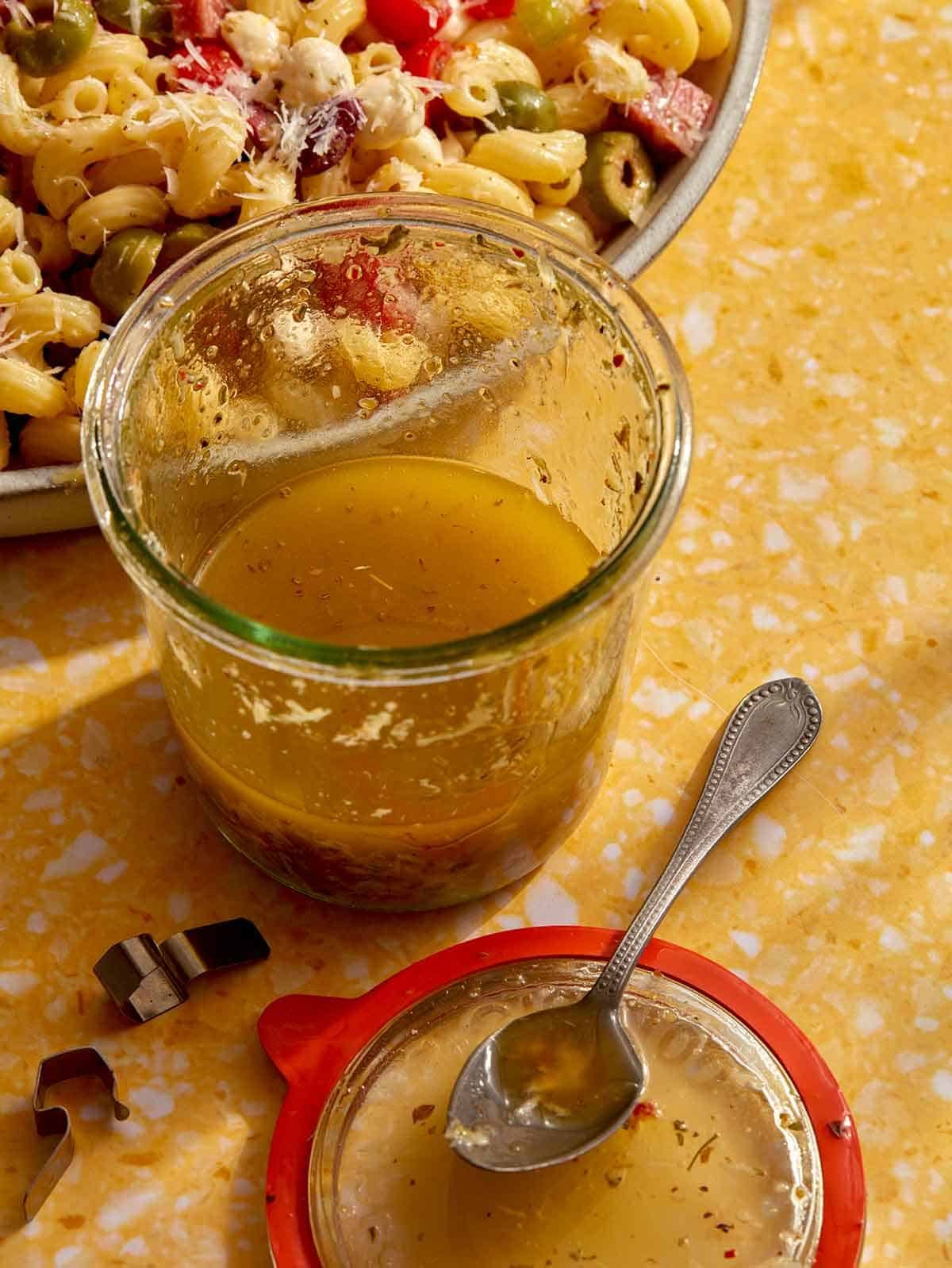 Freshly made Italian vinaigrette dressing in a jar with the lid next to it.