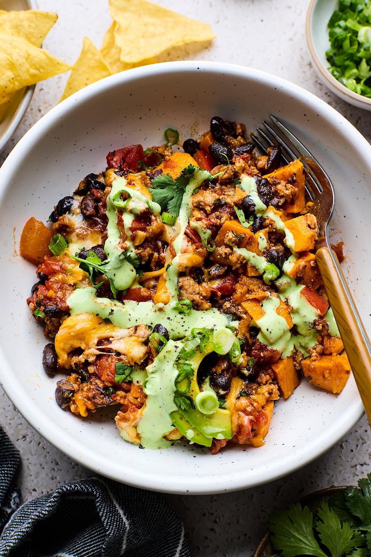 Sweet Potato Turkey Black Bean Bake in bowl with jalapeño ranch sauce and fork. 
