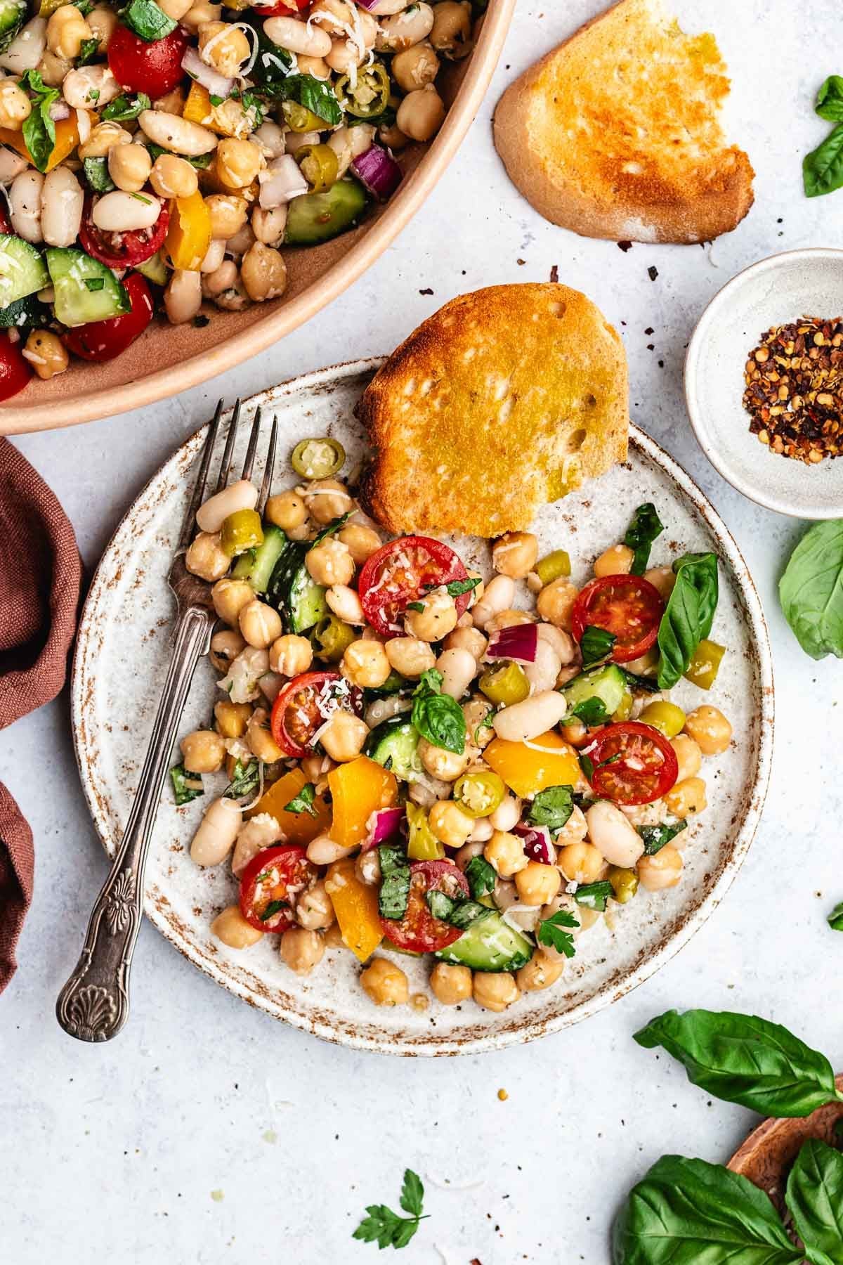 Italian bean salad on plate with fork and crusty bread. 