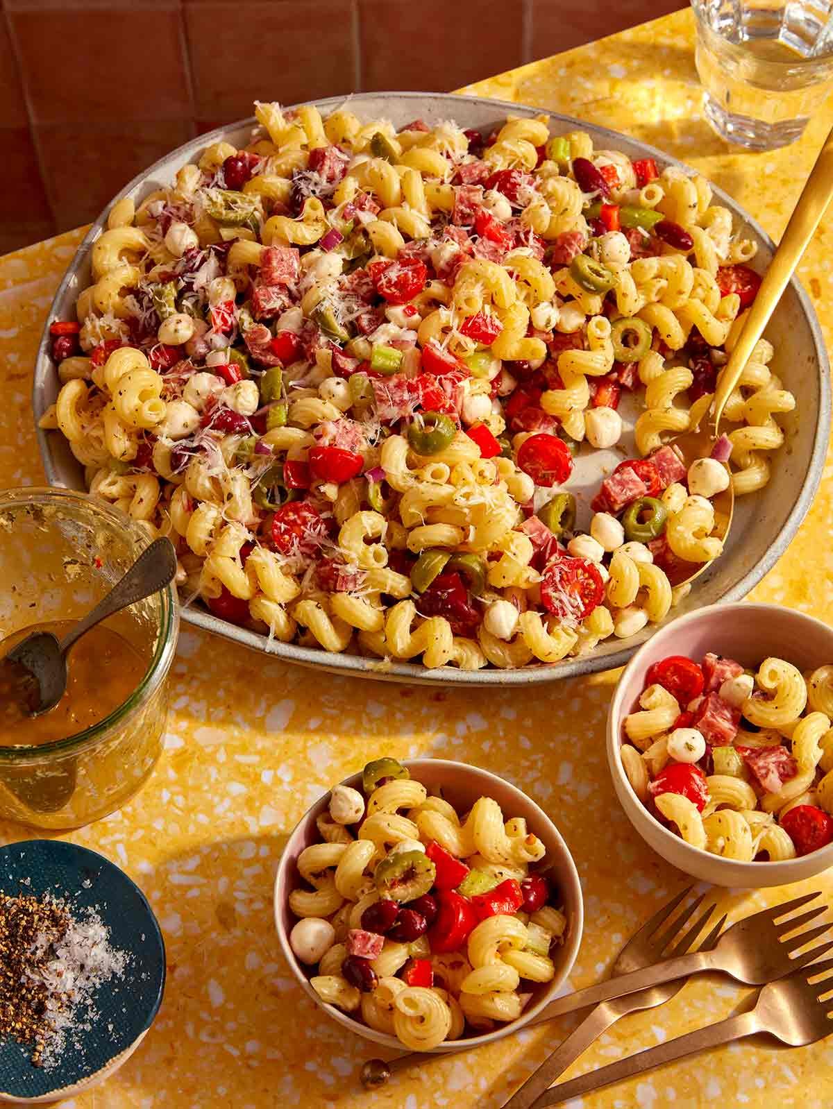 Pasta salad being served into small bowls.