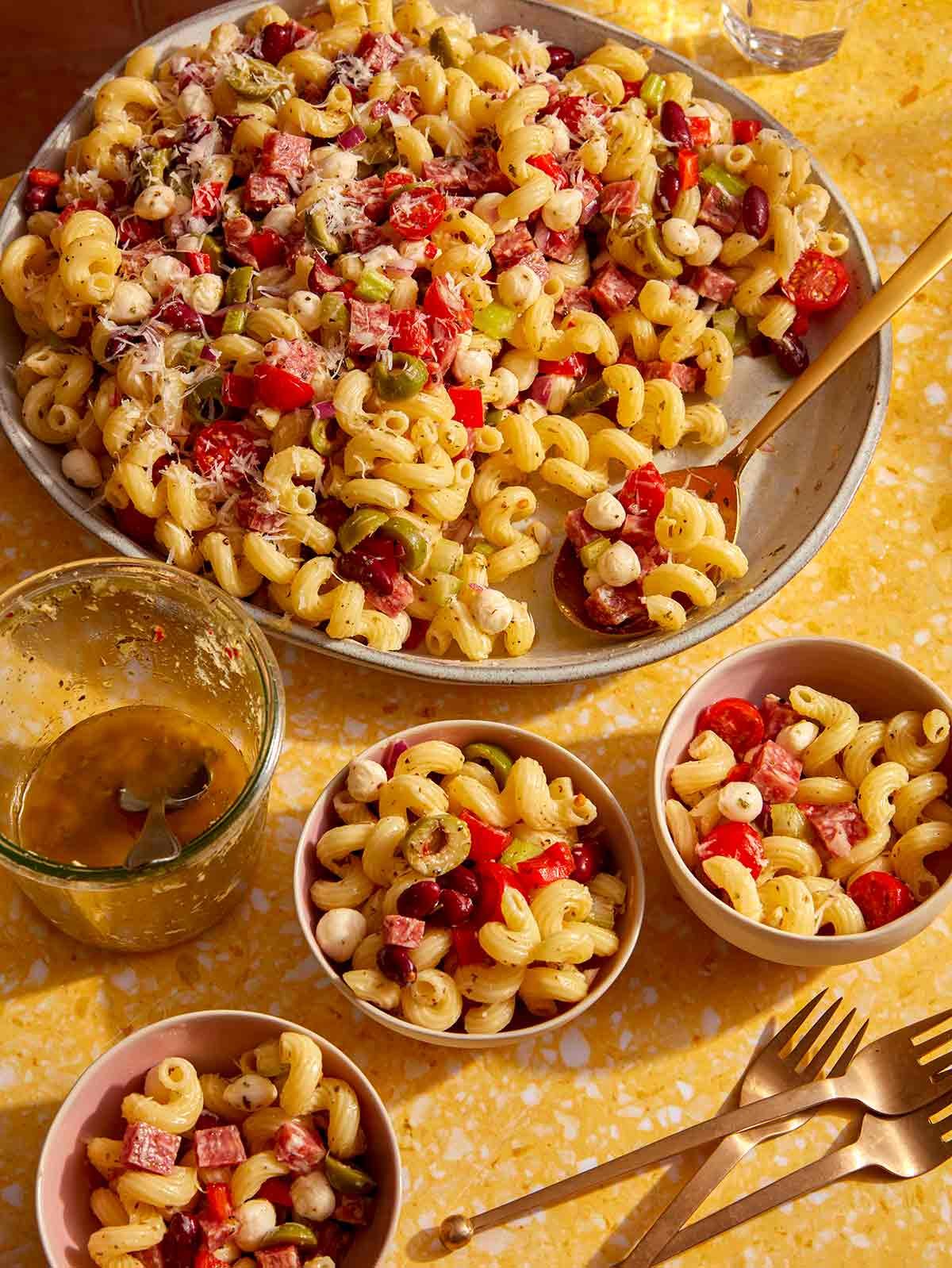 Pasta salad being served into small bowls.