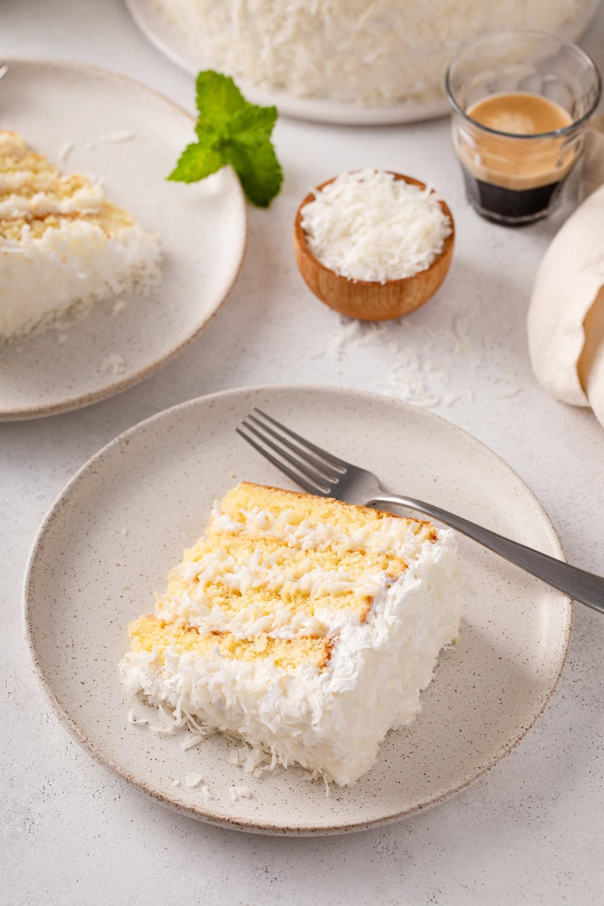 Plates of sour cream coconut cake on a countertop.