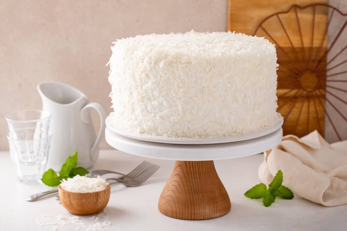 Side view of 3-day sour cream coconut cake on a cake stand.