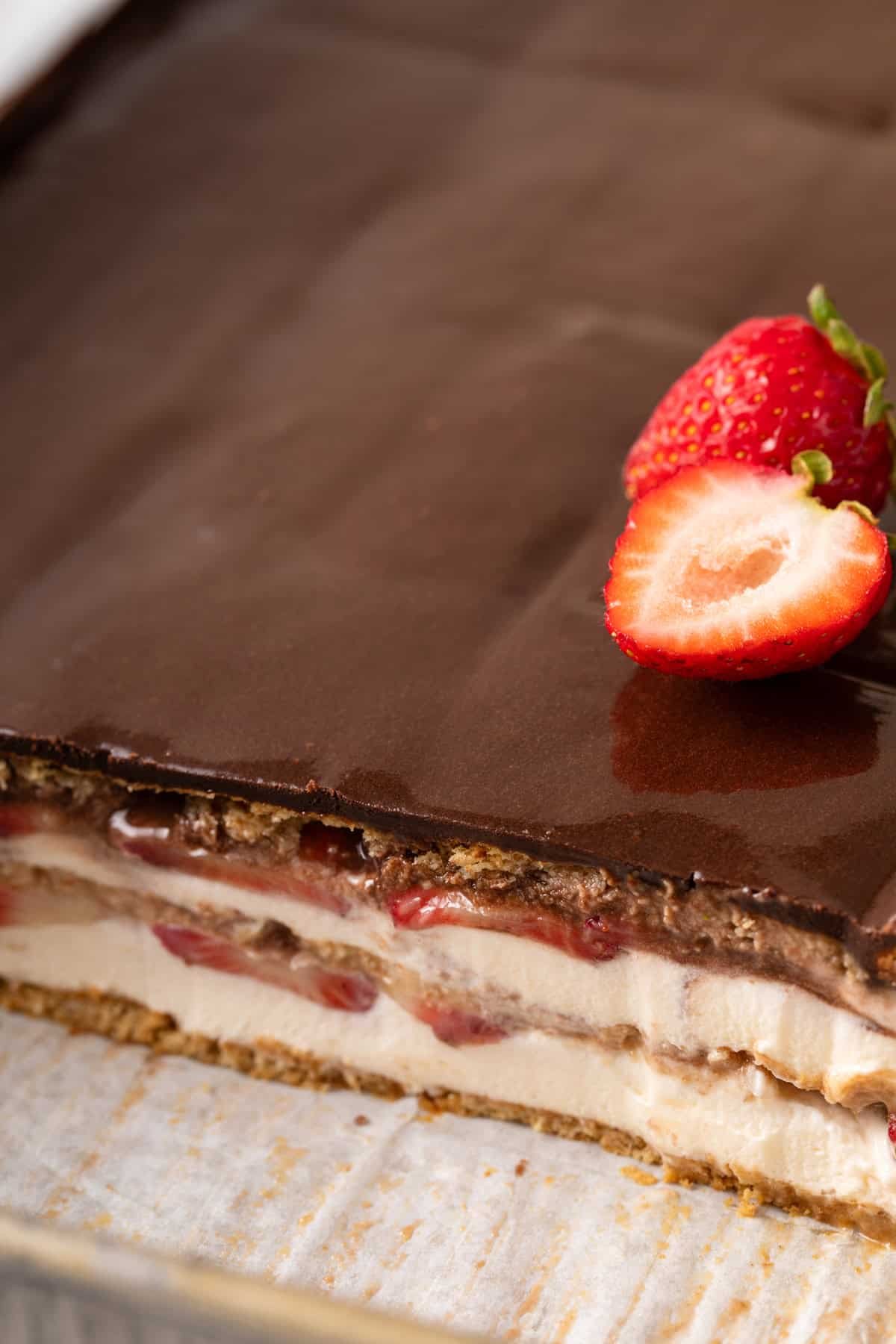 Strawberry eclair cake cut in a baking pan to show the layers.