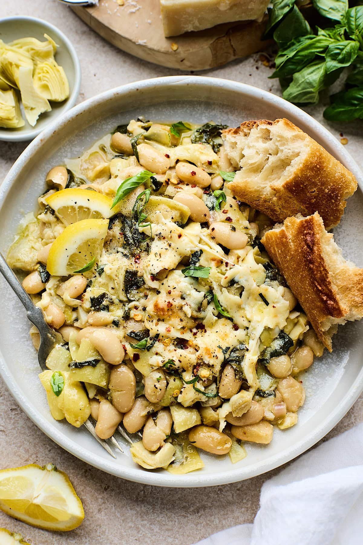spinach artichoke white bean skillet on plate with fork and crusty bread. 
