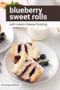 Blueberry sweet roll cut in half on a white plate in front of a glass of milk. Text overlay includes recipe name.