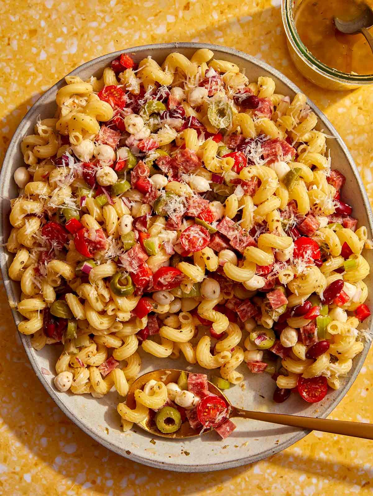 Pasta salad in a big bowl with a spoon in it.
