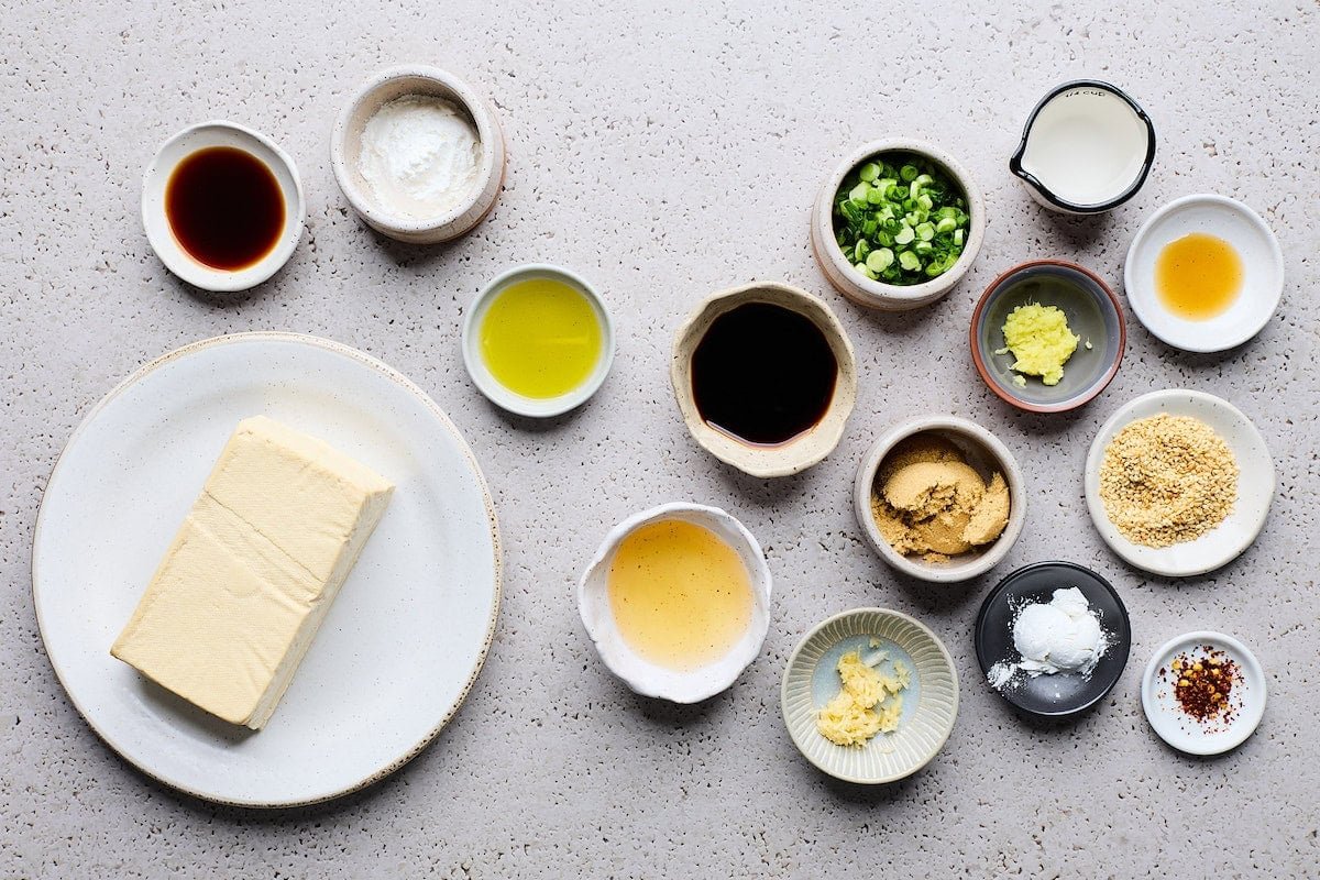 tofu on plate with ingredients in bowls to make crispy tofu teriyaki. 