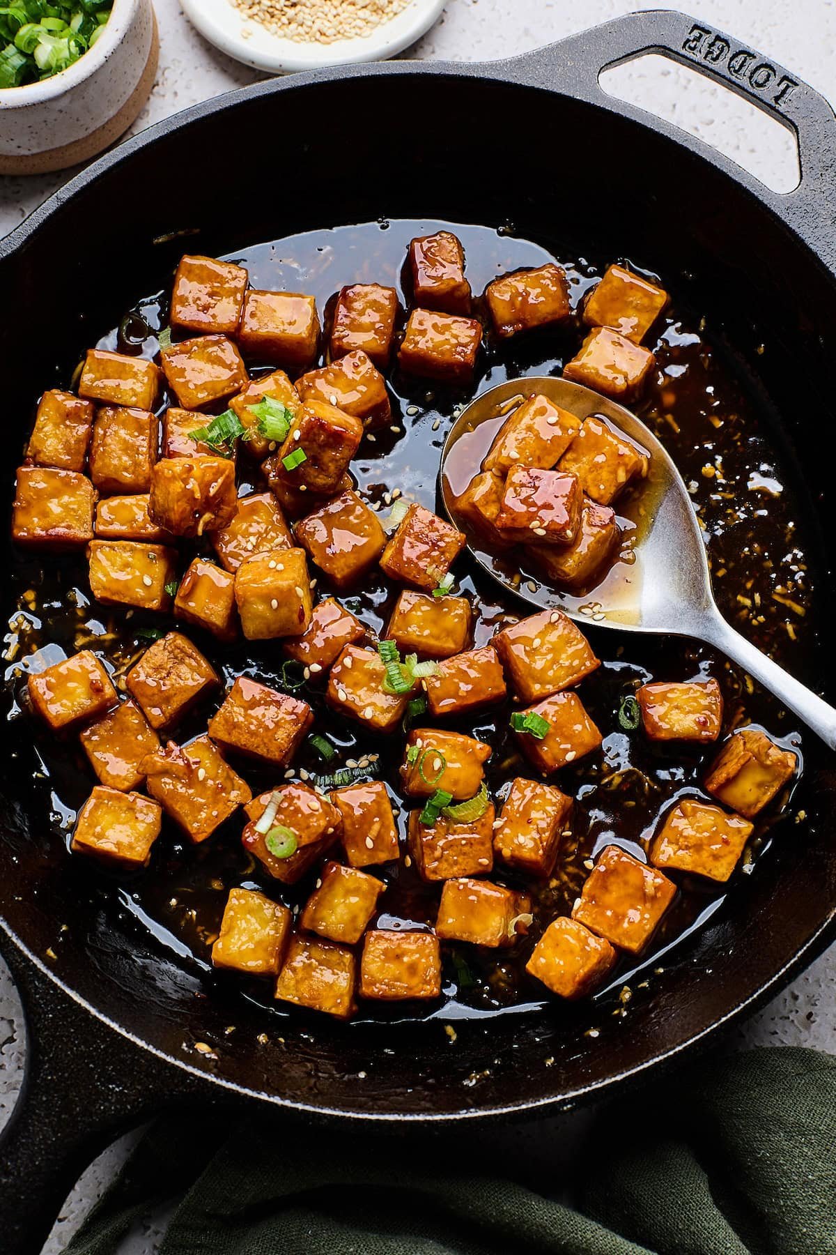 crispy tofu teriyaki in skillet with sauce and spoon. 