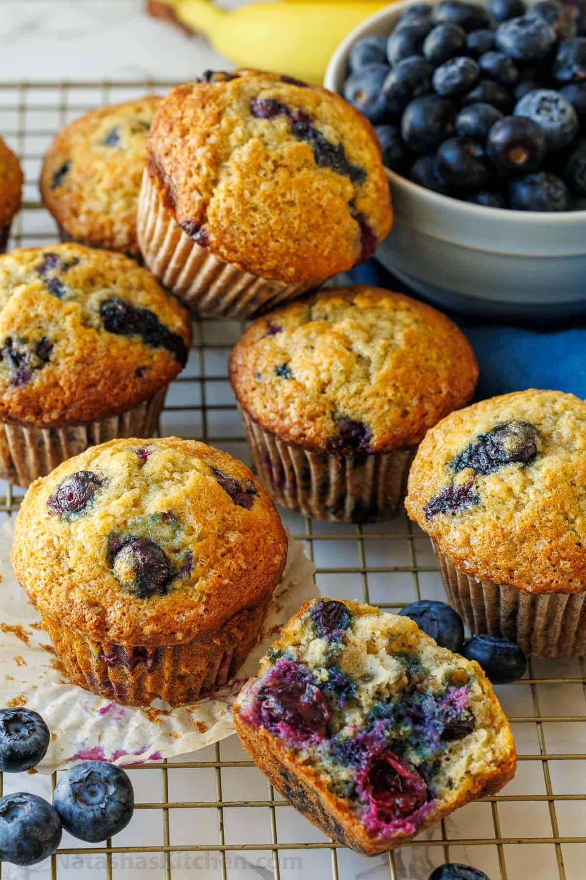 Blueberry banana muffins loaded with blueberries inside sitting with a bowl of blueberries