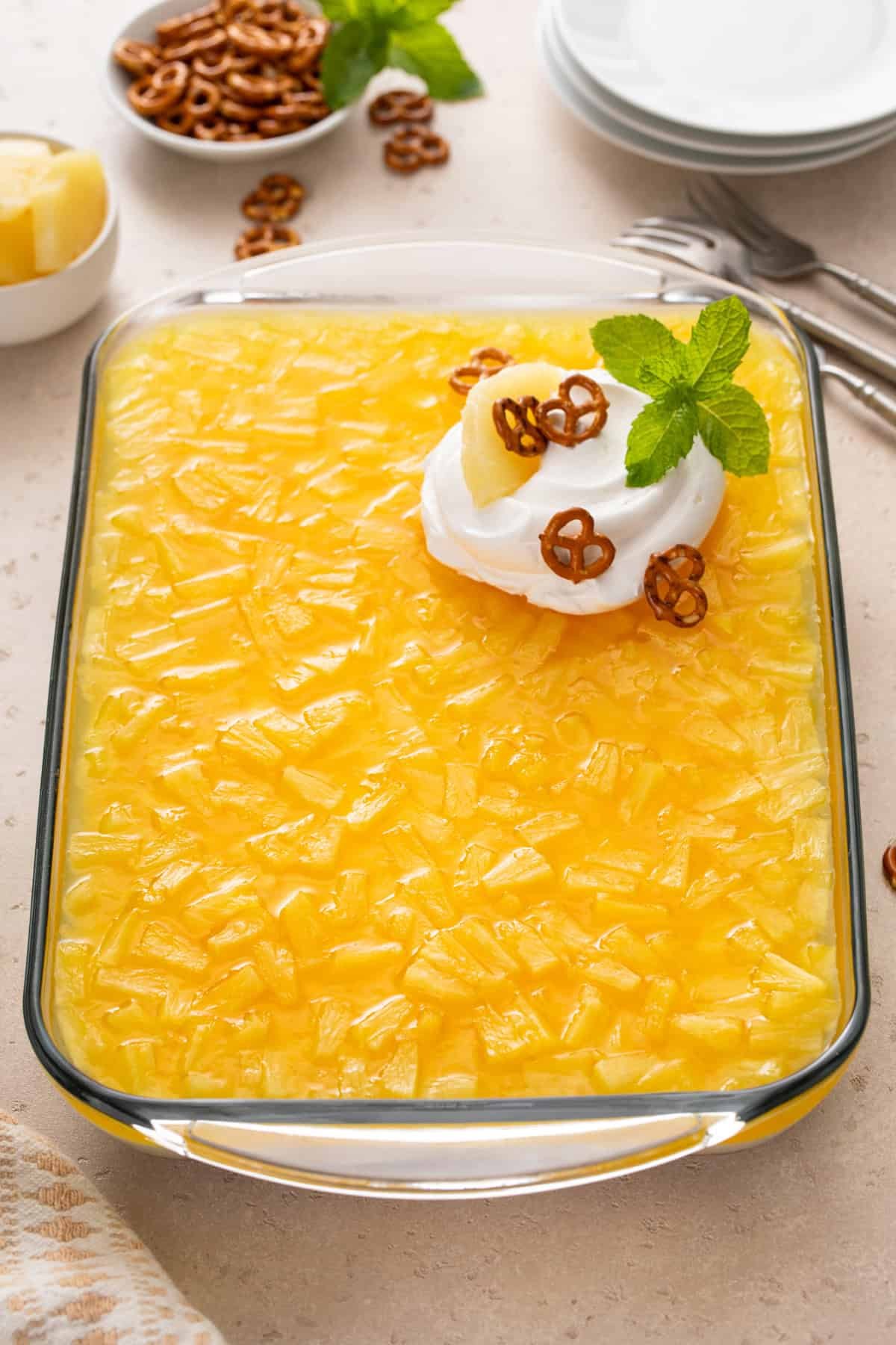 Chilled pineapple pretzel salad in a baking dish, garnished with a dollop of whipped cream.
