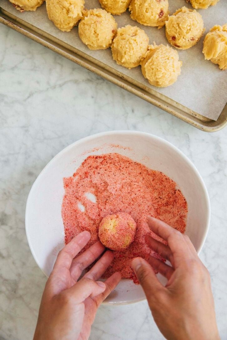 photo showing michelle from hummingbird high tossing a cookie dough ball in strawberry sugar