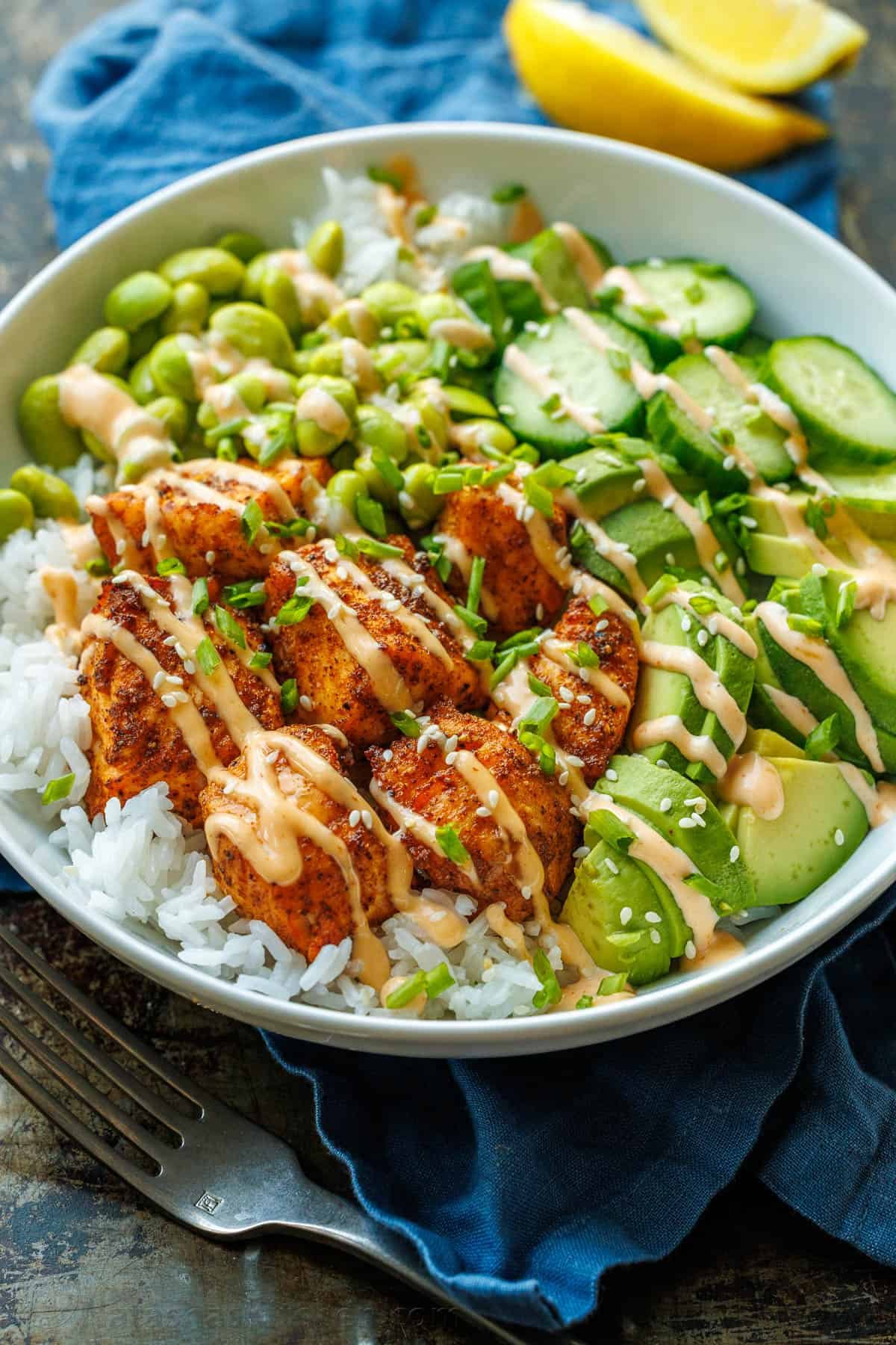 Salmon bowl recipe on a blue towel drizzled with mayo-based, 3-ingredient sauce